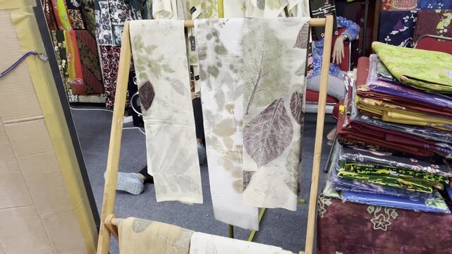 Handmade ecoprint fabrics hanging on wooden display rack