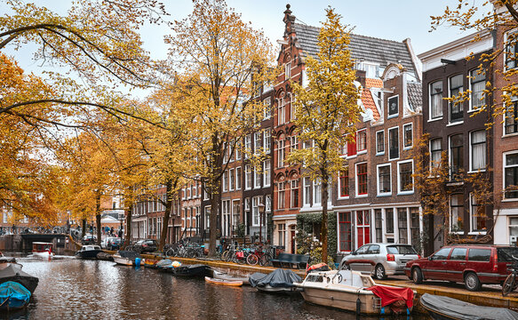 Amsterdam, Netherlands. Panoramic view of autumn Dutch city. Famous channel of Amstel river. Evening cityscape. Colorful sunset scene of famous travel destination in Europe. Romantic traveling place.