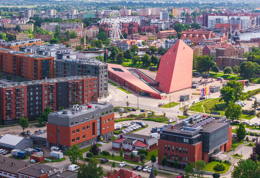Aerial view of the Museum of the Second World War featuring its iconic red angular design amidst modern urban development and green areas in Gdansk, Wojewodztwo pomorskie, Poland.