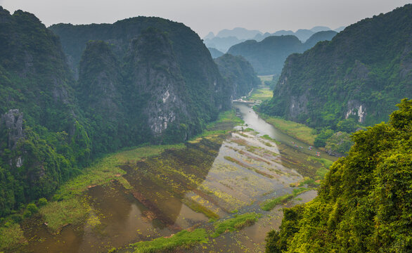 Aerial view of Tam Coc Bich Dong limestone karst mountains and the winding Ngo Dong River with lush vegetation and small boats in Nam Hoa Lu, Ninh Binh, Vietnam.