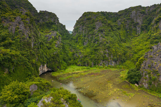 Aerial view of Tam Coc Bich Dong karst mountains and river with small boats carrying people through lush green landscape in Nam Hoa Lu, Ninh Binh, Vietnam.