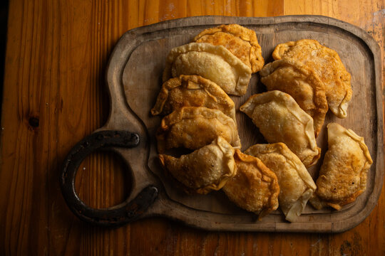 Overhead shot of homemade traditional empanadas served on a wooden cutting board
