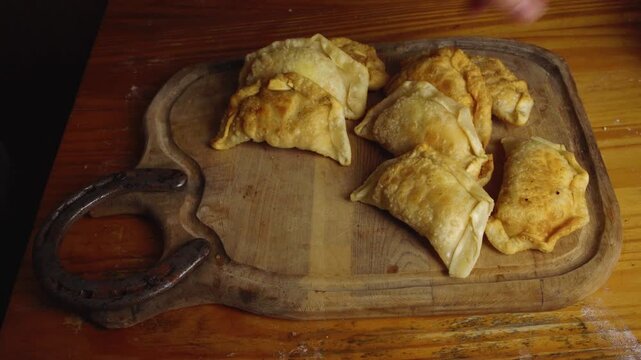 High Angle Shot of Hands Arranging Fried Golden Empanadas on Wooden Board
