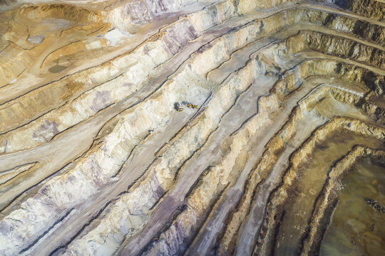 Aerial view of the Erzberg mine, featuring deep terraced open-pit excavation with heavy machinery and exposed rock layers in Eisenerz, Styria, Austria.