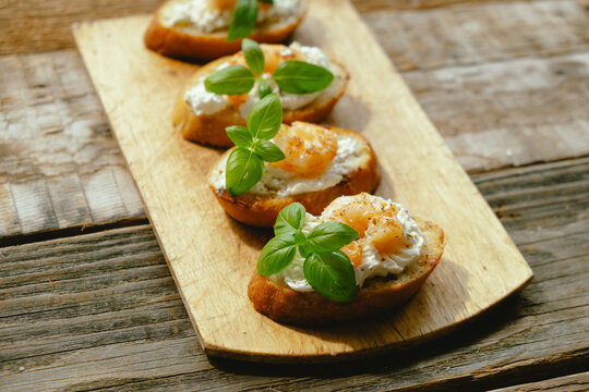 Bruschetta. Slices of toasted bread with feta, shrimp and fresh basil on wooden board.