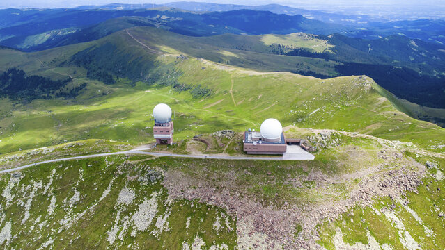 Aerial view of the Koralpe radar station with its two large white domes situated on the grassy mountain ridge in Wolfsberg, Carinthia, Austria.