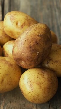 Vertical video. Heap of Raw Potatoes on a Wooden Background