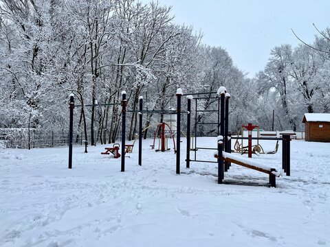 Parque infantil con columpios y barras de calistenia completamente cubiertos de nieve durante el invierno