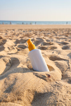 Sunscreen bottle standing in beach sand with ocean background