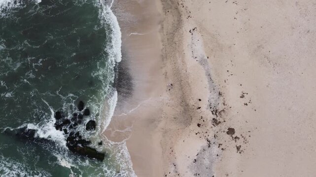 Aerial top down view of ocean waves on beach in paracas, peru
