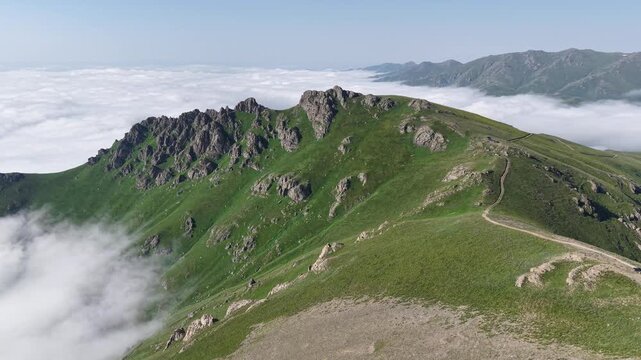 Aerial view of a green rocky mountain ridge above a sea of clouds․