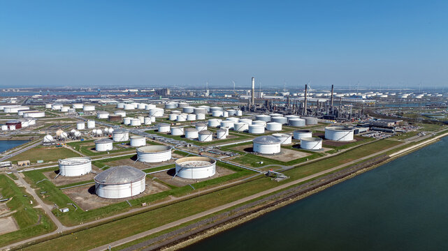 Aerial view of the extensive oil refinery and storage tank farm with numerous large white cylindrical tanks, industrial infrastructure, and pipelines in Rotterdam, South Holland, Netherlands.