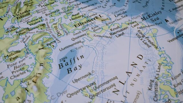 gliding macro view to greenland on a physical atlas map