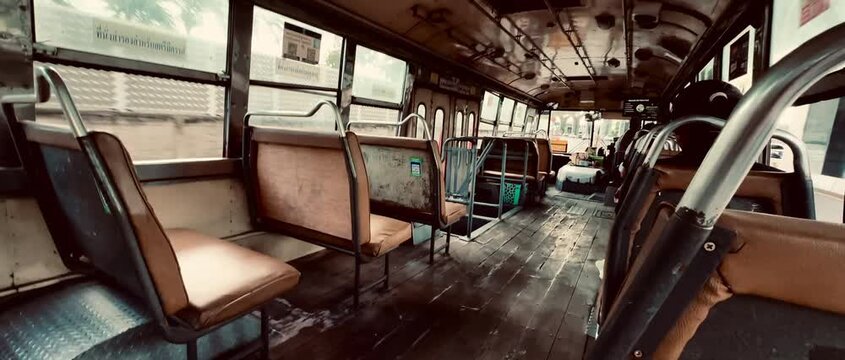 Interior view of an old vintage city bus with wooden floors and row of seats moving through public street. Authentic retro public transportation atmosphere for urban travel concept.
