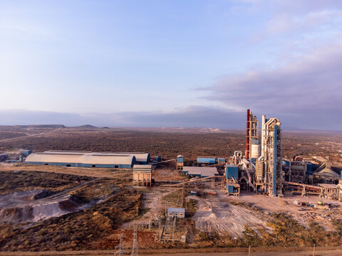 Aerial view of Simba Cement Merueshi industrial plant with large storage sheds, tall processing towers, and surrounding arid landscape in Kajiado, Kajiado County, Kenya.