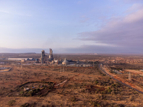 Aerial view of Simba Cement Merueshi industrial plant with tall silos and chimneys set in the arid savanna landscape of Kajiado, Kajiado County, Kenya.