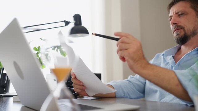 Businessman taking printed document from an office printer and read it seriously, review important information for work. Business analysis, document management and professional decision-making concept