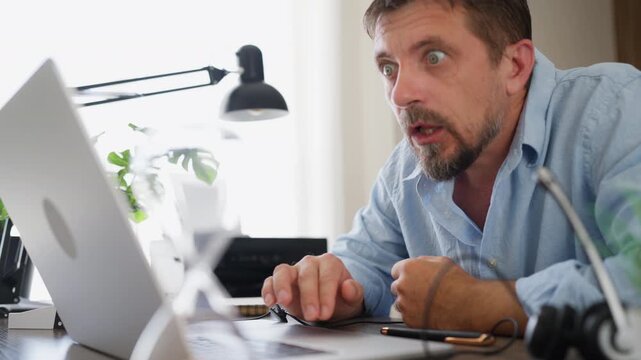 Excited businessman working from home, reacting with surprise and happiness after seeing positive news on his laptop. Business success, achievement, good news and professional celebration concept.