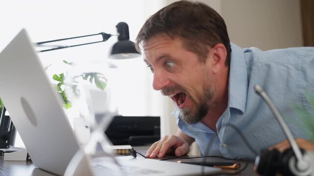 Happy businessman celebrating positive results while checking information on his laptop . Financial success, business growth, investment results and positive outcome concept.