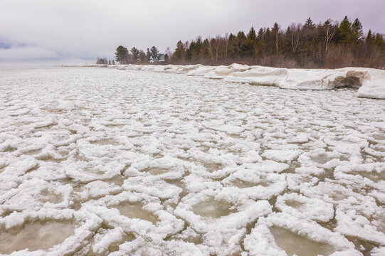 Aerial view of Sturgeon Point Lighthouse surrounded by ice floes and frozen water on Lake Huron in Harrisville, Michigan, United States.
