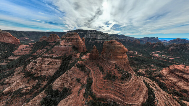 Aerial view of the iconic red rock formations, featuring rugged sandstone cliffs, desert vegetation, and dramatic cloud formations in Sedona, Arizona, United States.