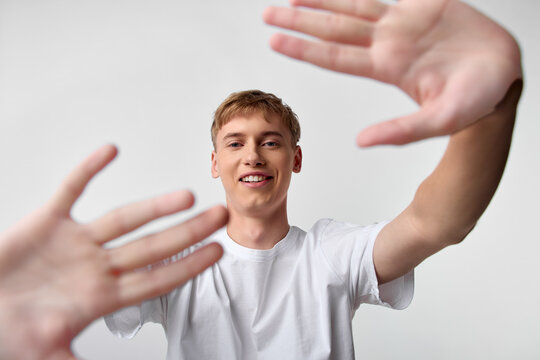 Hands reaching toward the camera with a smiling young man in a white tee creating a friendly connection, dynamic foreground gesture, conveying welcome collaboration help and active engagement in