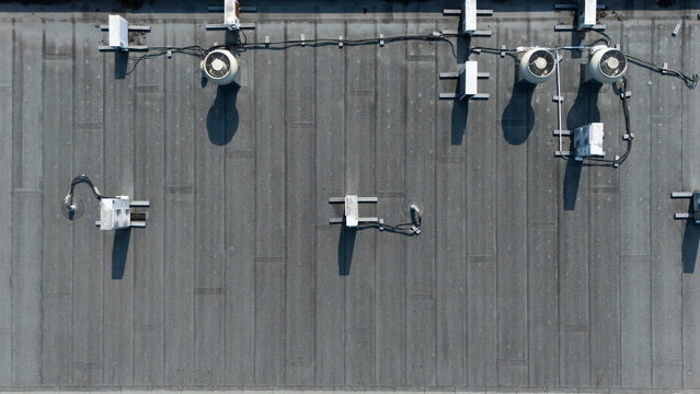 Aerial view of a flat commercial building roof featuring multiple HVAC ventilation units, electrical conduits, and vents in Apeldoorn, Gelderland, Netherlands.