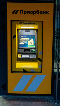 Bank ATM located outside a building in the evening with a bright screen and yellow front Priorbank ATM in Grodno, Belarus, July 18, 2026