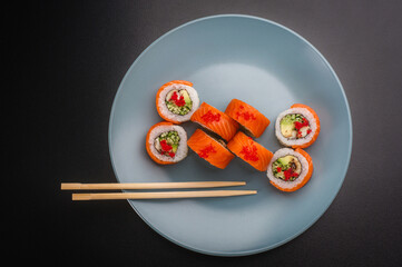 Top View Salmon Sushi Rolls with Tobiko and Chopsticks on Blue Plate © Ilias