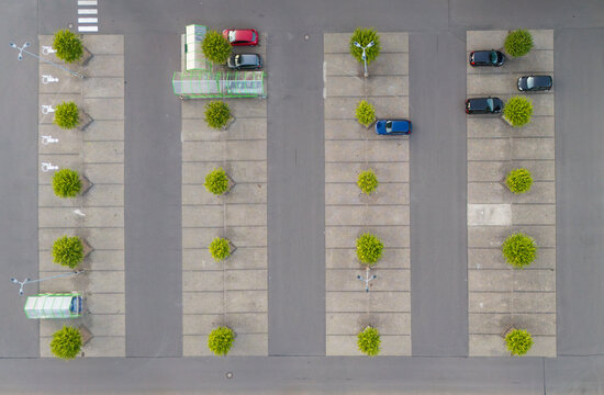 Aerial view of a parking lot with rows of trees separating parking spaces and several parked cars in Trier-Saarburg, Rhineland-Palatinate, Germany.