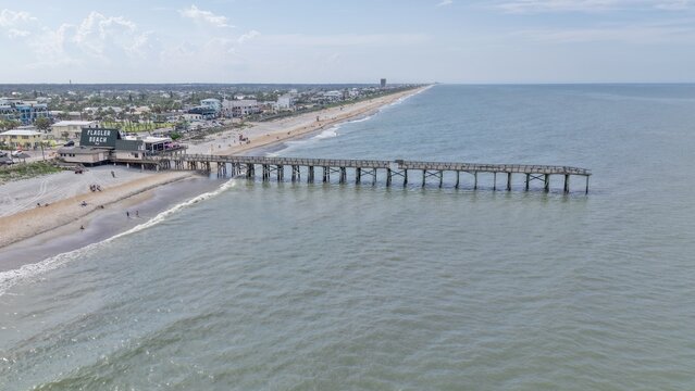 Aerial view of Flagler Beach Pier extending into the Atlantic Ocean with sandy coastline and coastal buildings in Flagler Beach, Florida, United States.