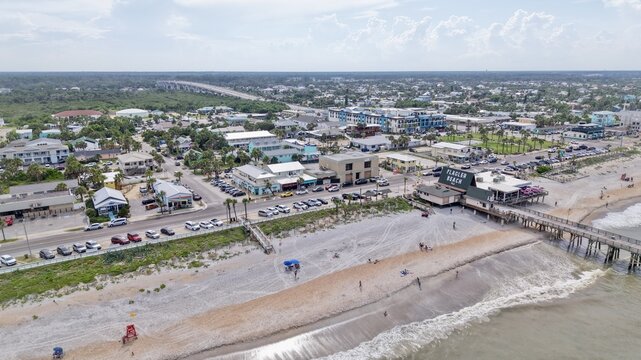 Aerial view of the Flagler Beach pier and surrounding coastal town, featuring sandy beaches, ocean waves, and local buildings in Flagler Beach, Florida, United States.