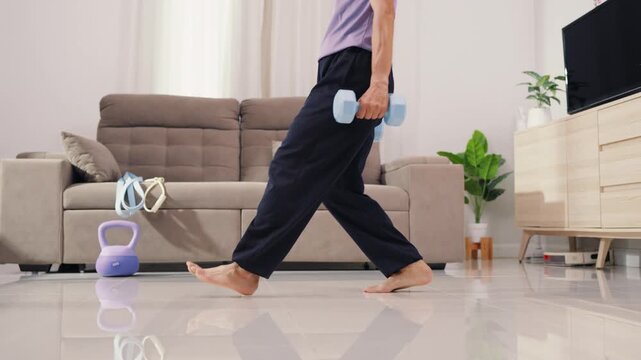 Senior Asian male patient doing squat exercise with dumbbell for physical therapy and muscle rehabilitation. Dedicated elderly man focusing on active fitness and healthy recovery.