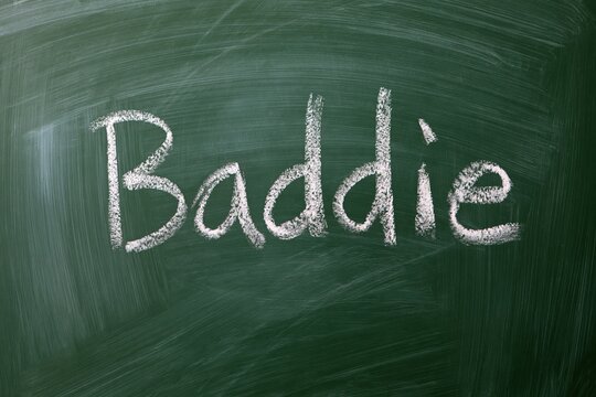 The word "Baddie" written in chalk on a green chalkboard, representing a slang term for a confident and attractive person.