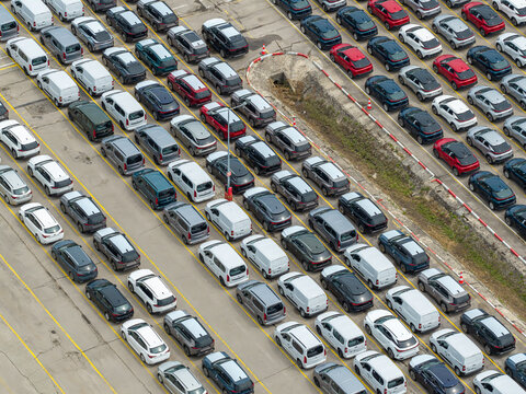 Aerial view of rows of new cars and vans parked in a large industrial car forwarding lot in Poland.