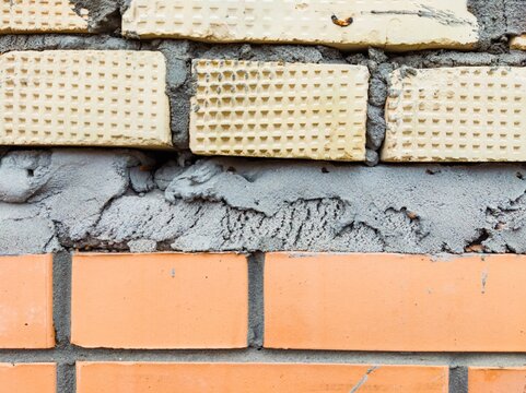 Exposed brick wall with uneven cement layer
