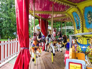 Colorful carousel horses on wooden platform outdoors © IbragimovN