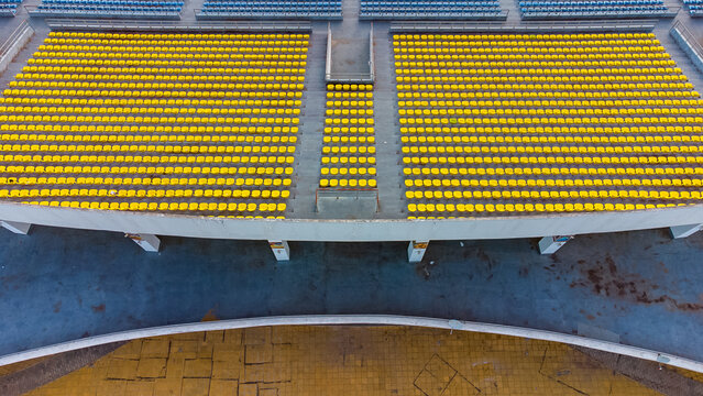 Aerial view of the empty yellow seating rows at Cape Coast Sports Stadium, showing the geometric layout of the stands in Cape Coast, Central Region, Ghana.