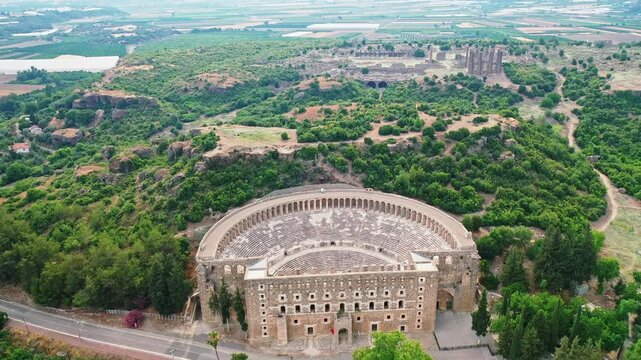 Aerial view of the ancient Roman amphitheater in Aspendos, Antalya, showcasing one of Turkey's most famous historical landmarks. Majestic drone shot over well-preserved stone ruins.