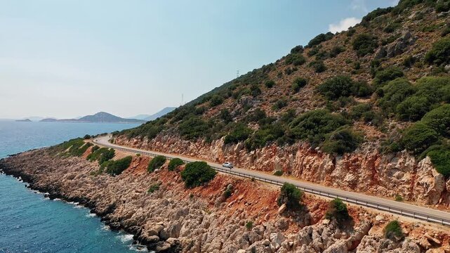 Antalya Kas coastal road aerial view curving along turquoise Mediterranean Sea. Scenic drone video of asphalt highway overlooking dramatic cliffs and coast.