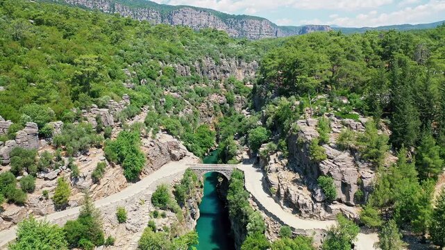 Aerial view of the historic stone bridge at Koprulu Canyon in Antalya, showcasing the ancient architecture over the deep river valley. Majestic drone flight in Manavgat, Turkey.