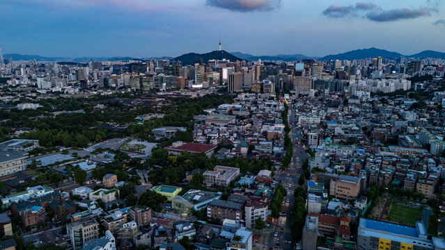 Aerial view of N Seoul Tower rising above the dense urban landscape with historic palaces, modern skyscrapers, and lush green spaces in Seoul, Seoul, South Korea.