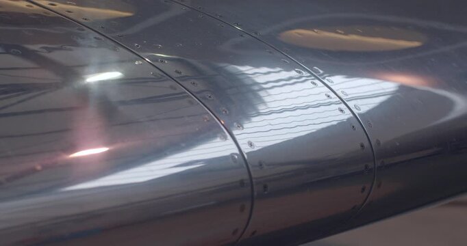 Shiny airplane wings featuring detailed rivet arrangements and reflective surfaces. Polished aircraft wing displays intricate line work along curved panels and shiny rivet details