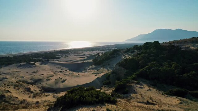 Patara sand dunes sunset aerial view capturing the dramatic golden hour light over the vast desert-like landscape in Antalya, Turkey. Majestic drone shot of coastal dunes.