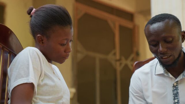 Black couple serious conversation on porch. Man and woman review paper with focused expressions, calm tone, white shirts, close seating, post date reflection and planning future steps with supportive