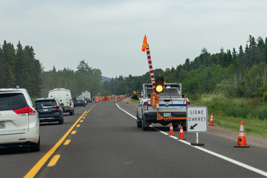 Quebec, Canada, 30 July 2026 : Vehicles queue on a highway at a road construction zone with a mobile traffic light and barrier arm.
