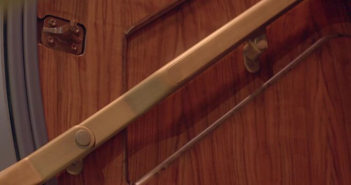 Brass handrail hinge installed on wood with visible tension and screws. Closeup image showcasing brass hinge attached to wooden surface with tension and screw details visible