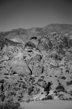 Hiking to Heart Rock. Three people hike through the Alabama Hills toward the Heart Rock. The rock has a hole shaped like a heart.