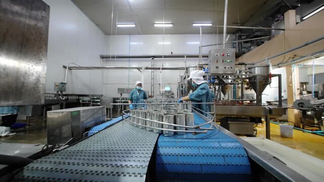 Workers handle equipment in a factory during a busy production process in the food industry