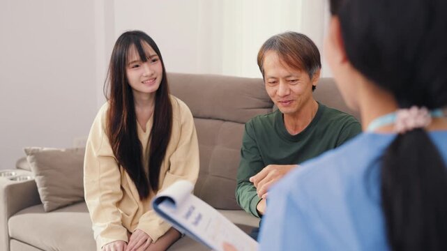 Senior Asian father and daughter visiting friendly female doctor for medical health consultation on sofa. Professional healthcare physician providing reliable healing advice.